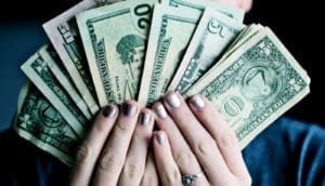 hands with silver nail polish hold money