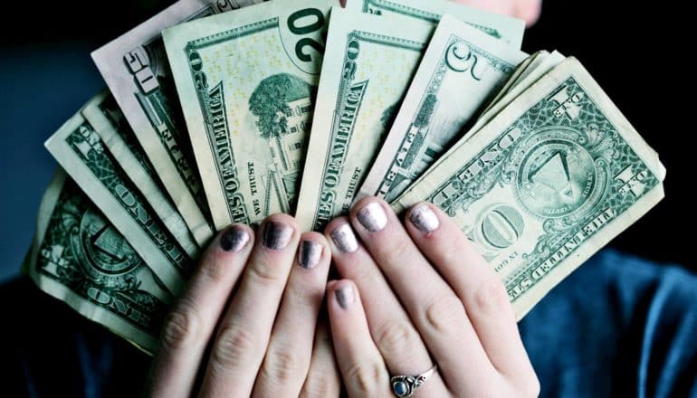 hands with silver nail polish hold money