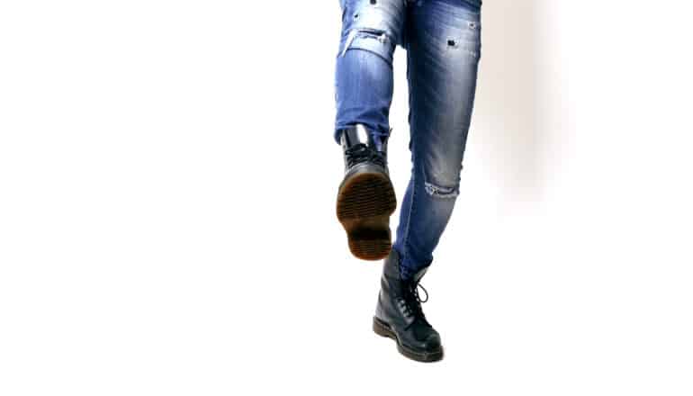 lower half of person in jeans and boots kicks a foot