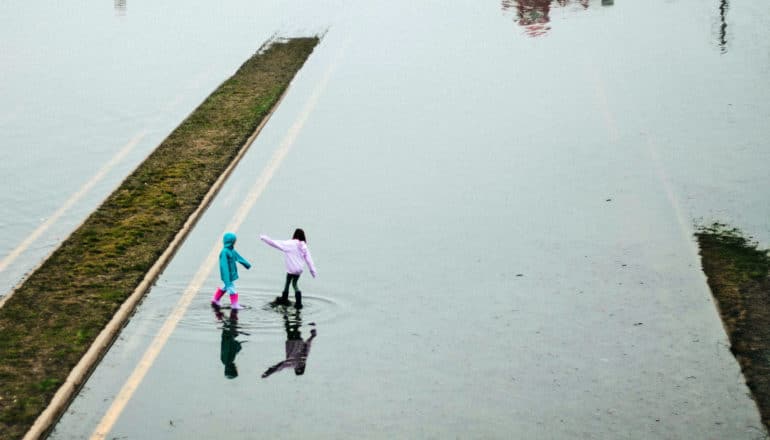 two kids play in flooded road