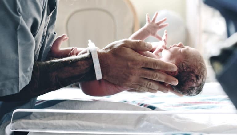 father picks up newborn baby