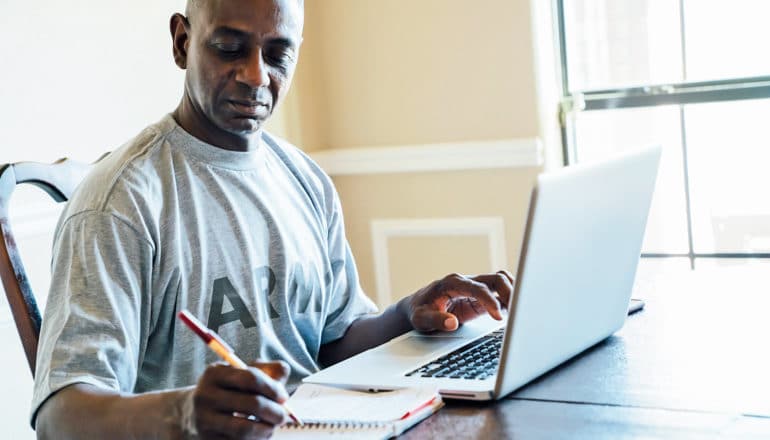 man in army t-shirt uses laptop