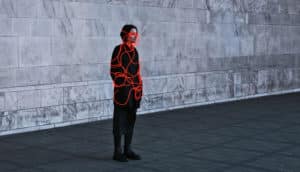 person in black clothes, in gray space, with red neon wires on body