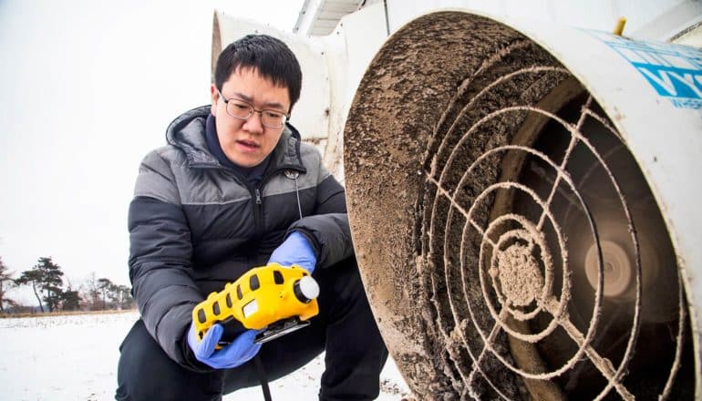 man kneels with sensor near dirty vent