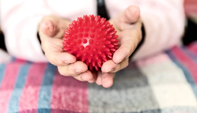 massage ball in hands of elderly woman