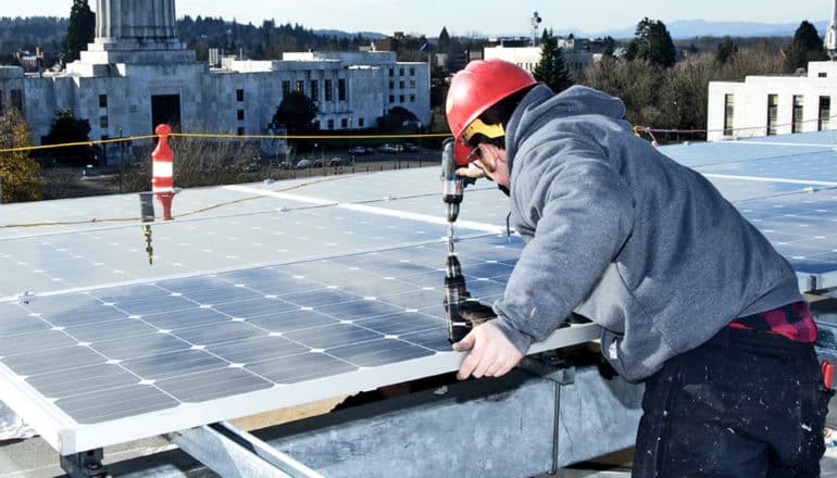 man installing solar panels on roof