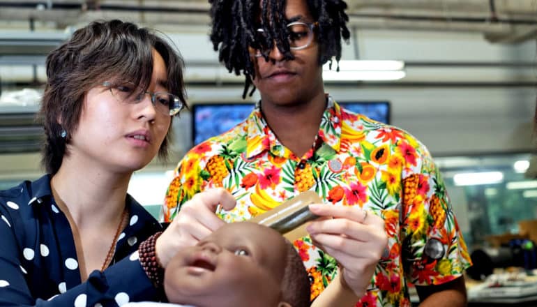 two students put sensor on a baby doll's head