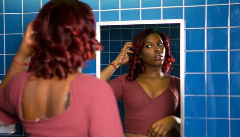 young trans woman looking in mirror