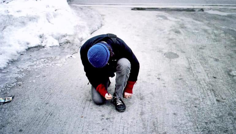 tying shoe in driveway