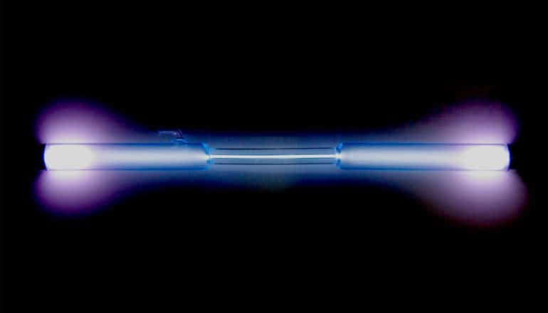 tube of xenon glows blue and purple on black