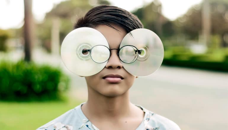 Young man wearing CDs in glasses (robots concept)