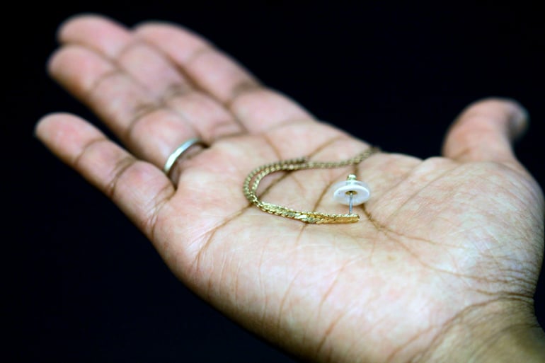 gold earring with back in palm of hand