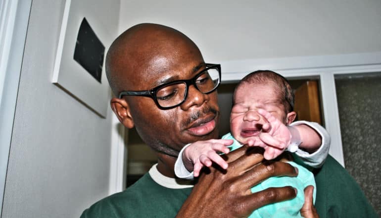 older dads - man holding fussy newborn baby