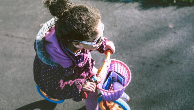 girl in sunglasses riding pink bike