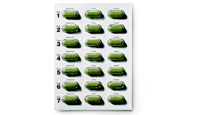 medication adherence - green pills in blister pack with daily schedule