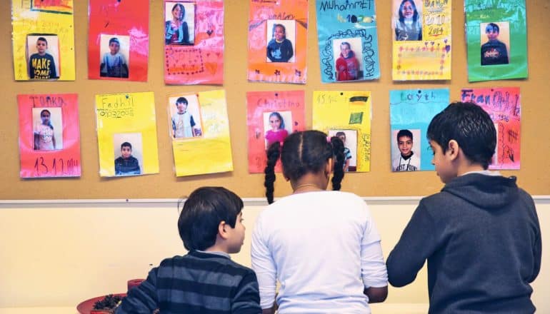 three children in front of colorful posters in classroom