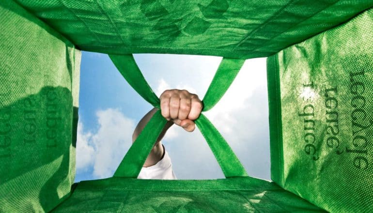hand holds green bag from below