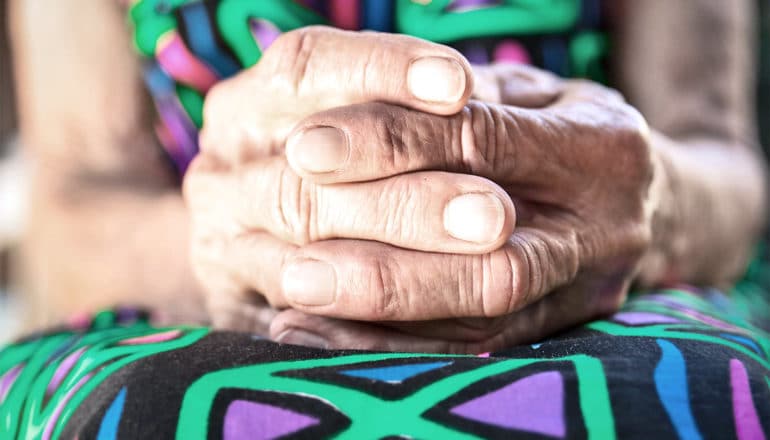 older woman's hands on colorful dress (rapamycin concept)
