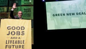 Senator Markey at podium in front of 'green new deal' slide