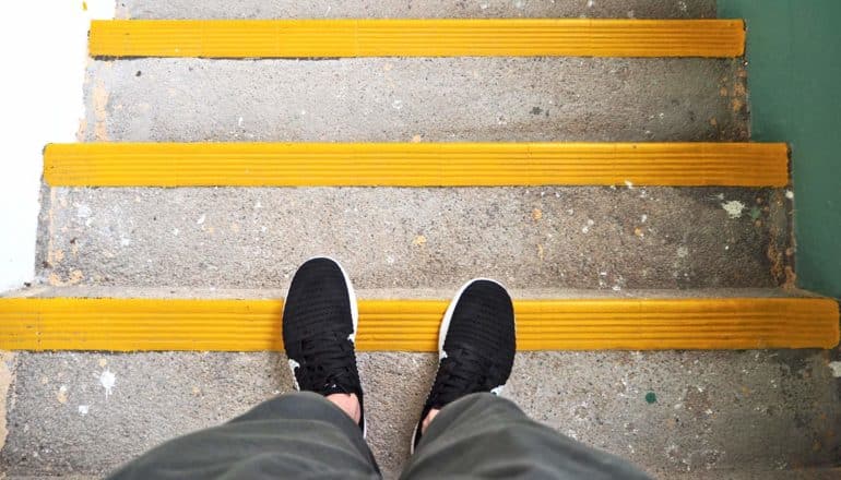black sneakers on yellow-edged stairs