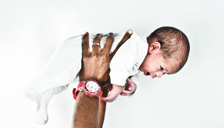 man's hands hold new baby in the air