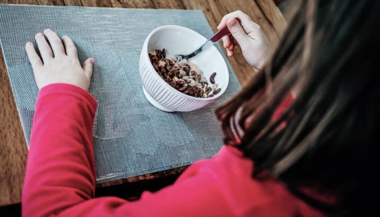 child in pink shirt eats cereal