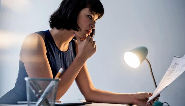 female executive reads paper by lamp