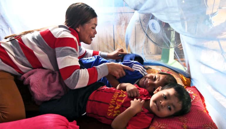 Family under mosquito net (malaria drug resistance concept)