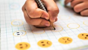 kid hand holds pencil on worksheet