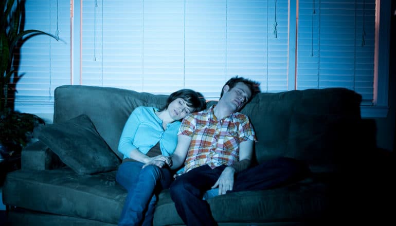 new parents asleep on couch