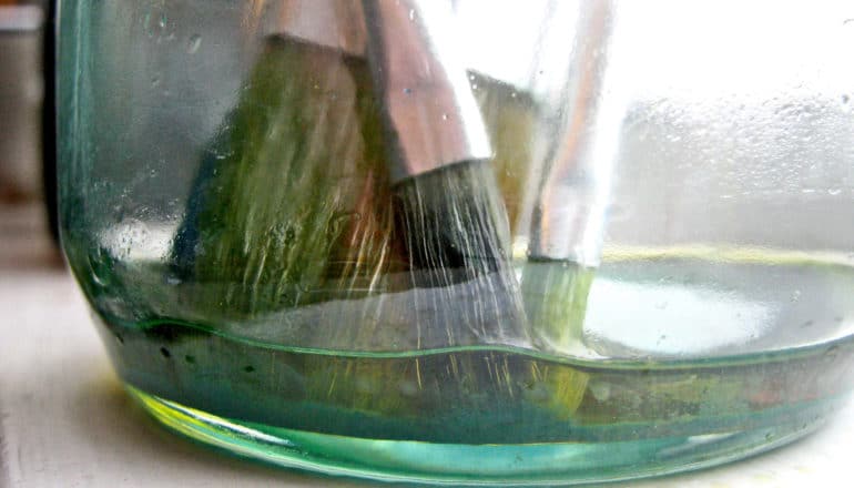 paintbrushes in jar of linseed oil