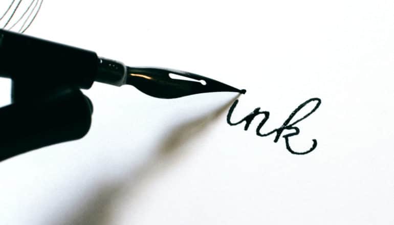 pen writes the word "ink" on white paper