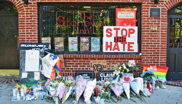 stonewall inn with flowers and sign that says "stop the hate"
