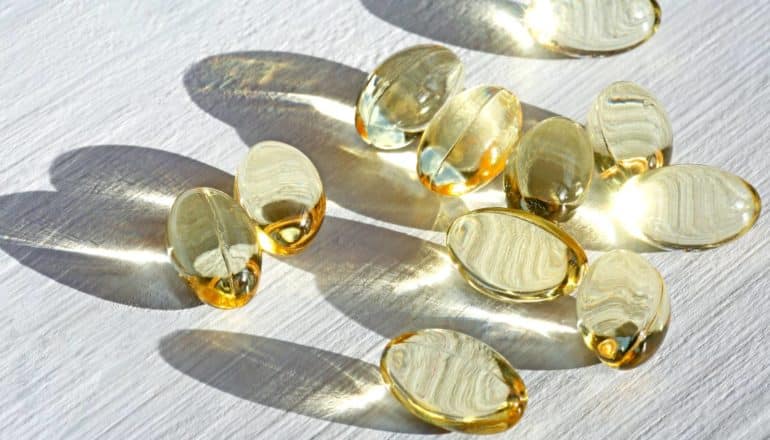 vitamin D capsules on white wood