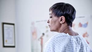 woman in gown waits in doctor's office