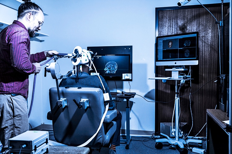 A researcher sets up sets up the coil that will deliver the Senders’ responses directly to the brain.