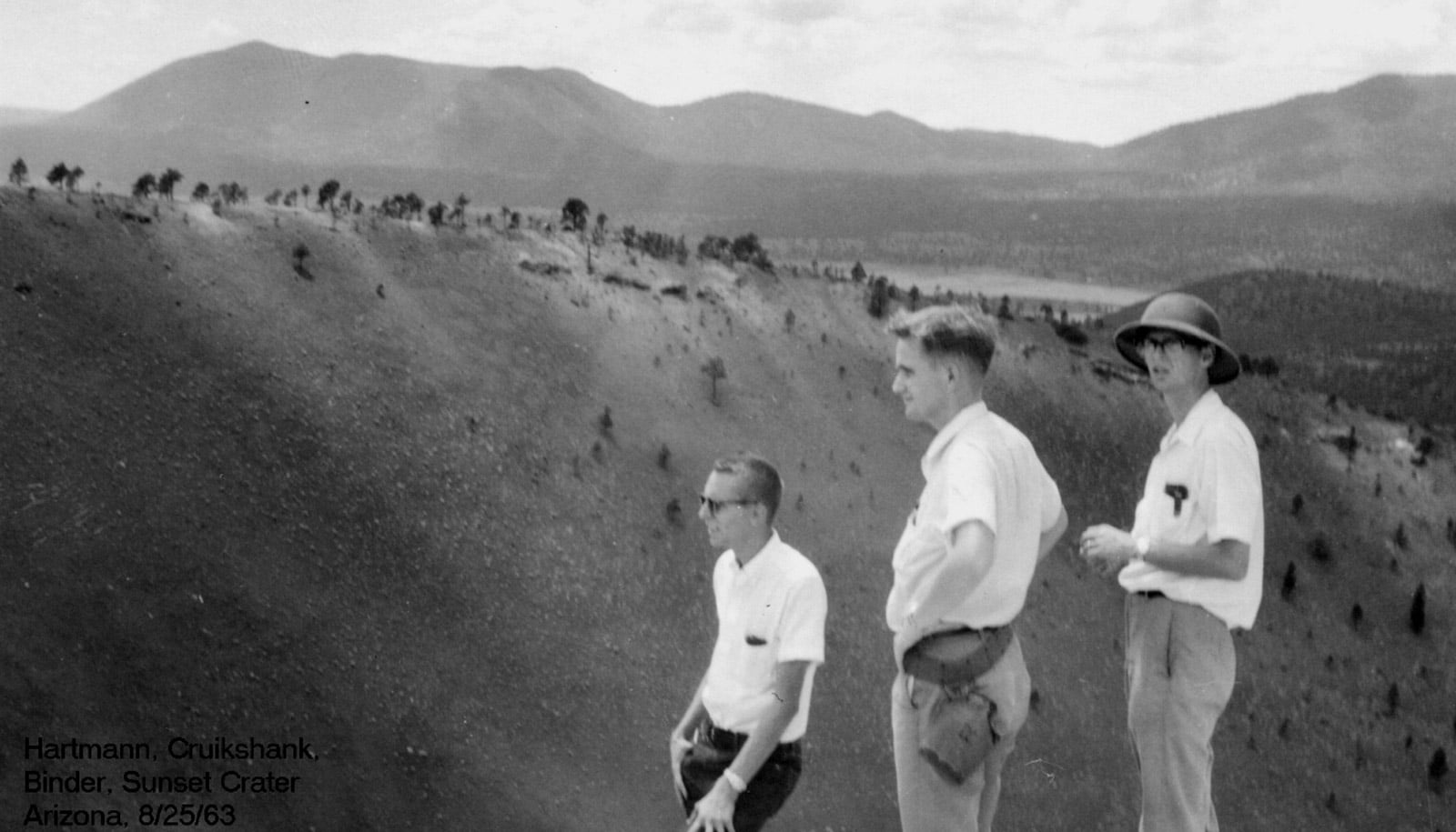 three men stand in front of desert landscape