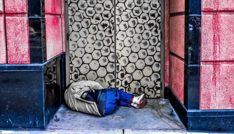 person sleeping in doorway - homelessness and legal debt