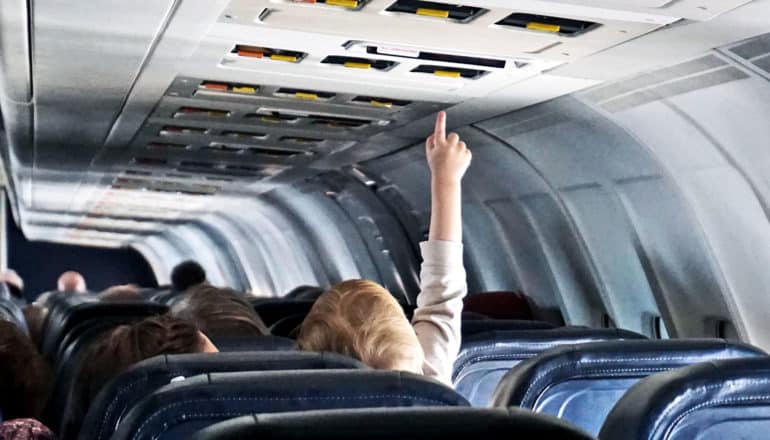 kid reaching for button on plane (Airplane first-aid kits concept)