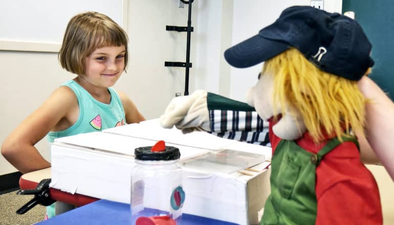 A young girl plays the trust game with a puppet