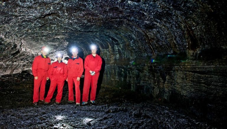 four people in red suits in lava tubes