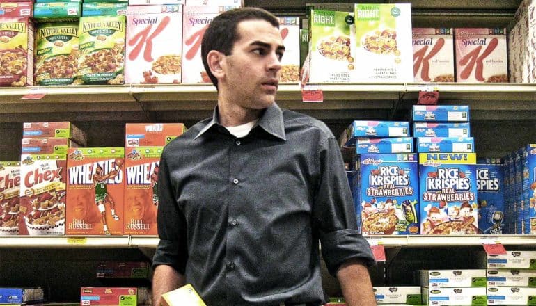 confused man in the cereal aisle (ultra-processed foods concept)