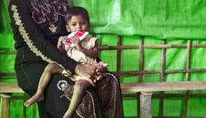 child on mother's lap eats therapeutic food for malnutrition