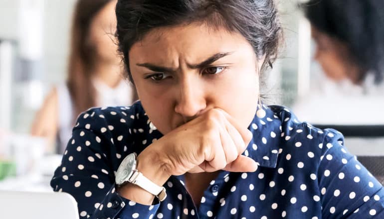 stressed woman covering mouth (frog in your throat concept)