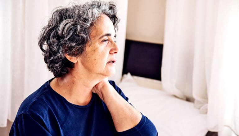 Tired woman sitting on bed (Alzheimer's disease concept)