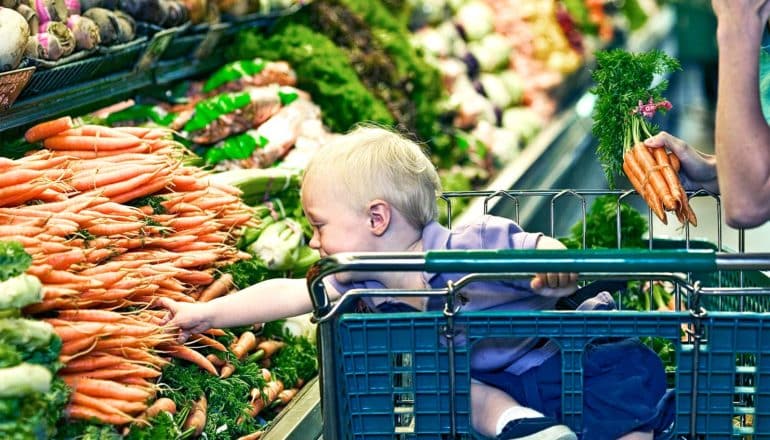 toddler reaching for veggies (new parents concept)