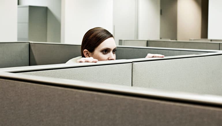 woman peeking out of cubicle (cheaters concept)