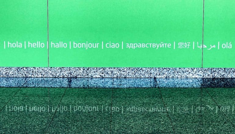 green wall with engraved text, "hello" in English, French, Spanish, and other languages