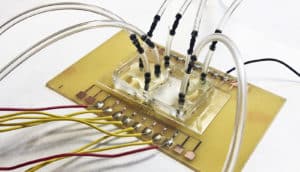 yellow-ish rectangle with a row of wires emerging from one side and clear tubes coming out from the top