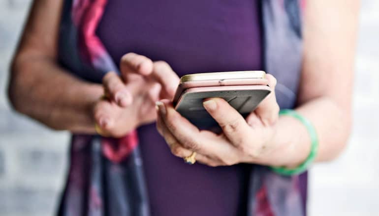 older person in purple holds phone in case and taps with finger